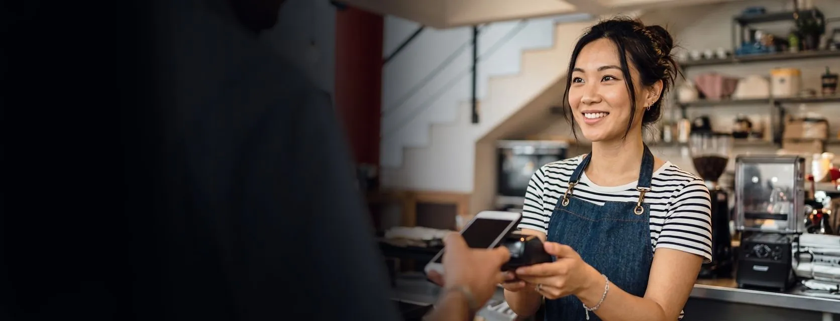 A cafe worker smiling while holding a card machine