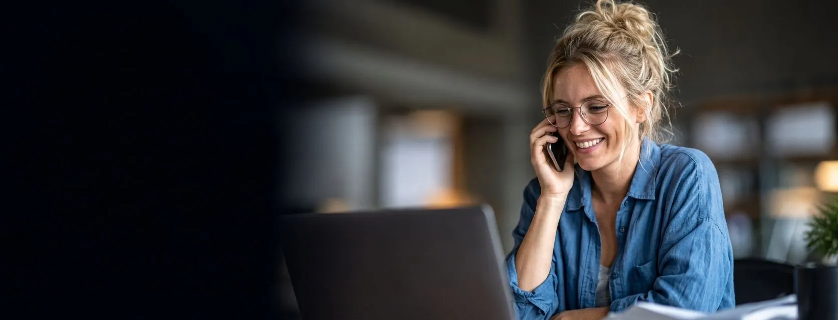 A business owner smiling while taking a phone call at her desk