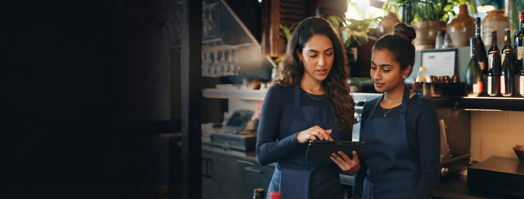 Two colleagues checking a tablet together in a cafe bar
