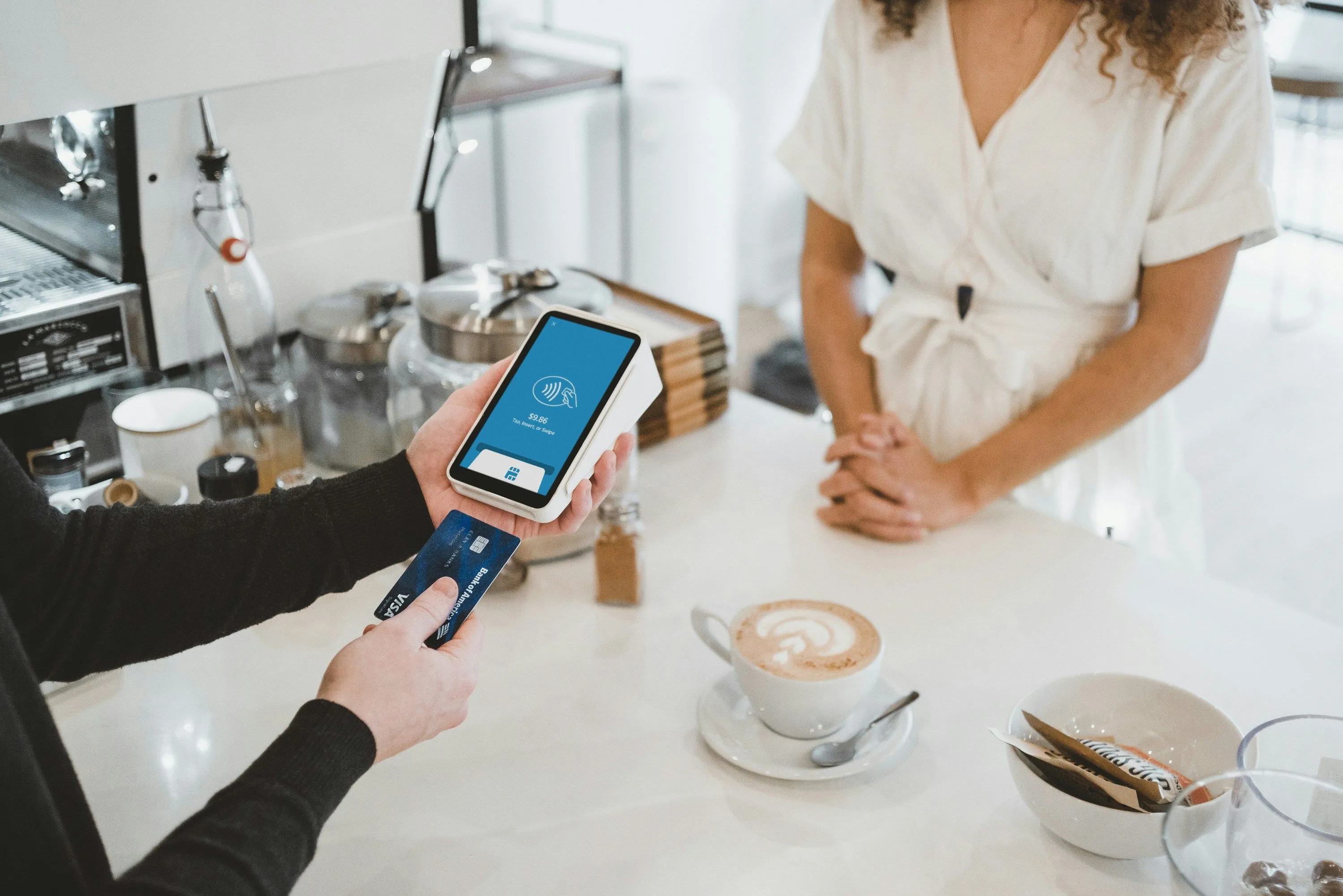 A barista taking a contactless payment at a cafe counter