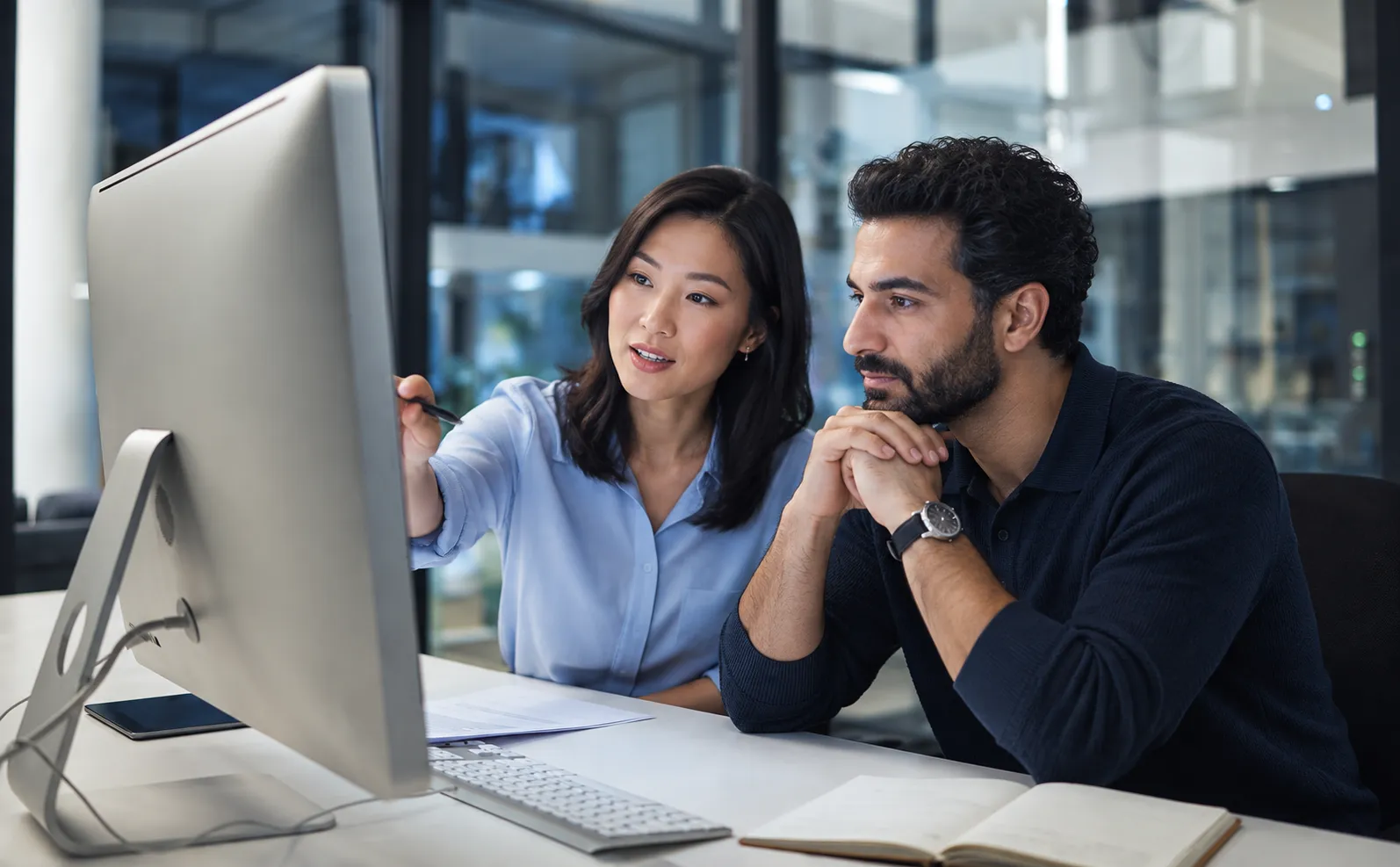 Two colleagues discussing a website checkout shown on a desktop monitor