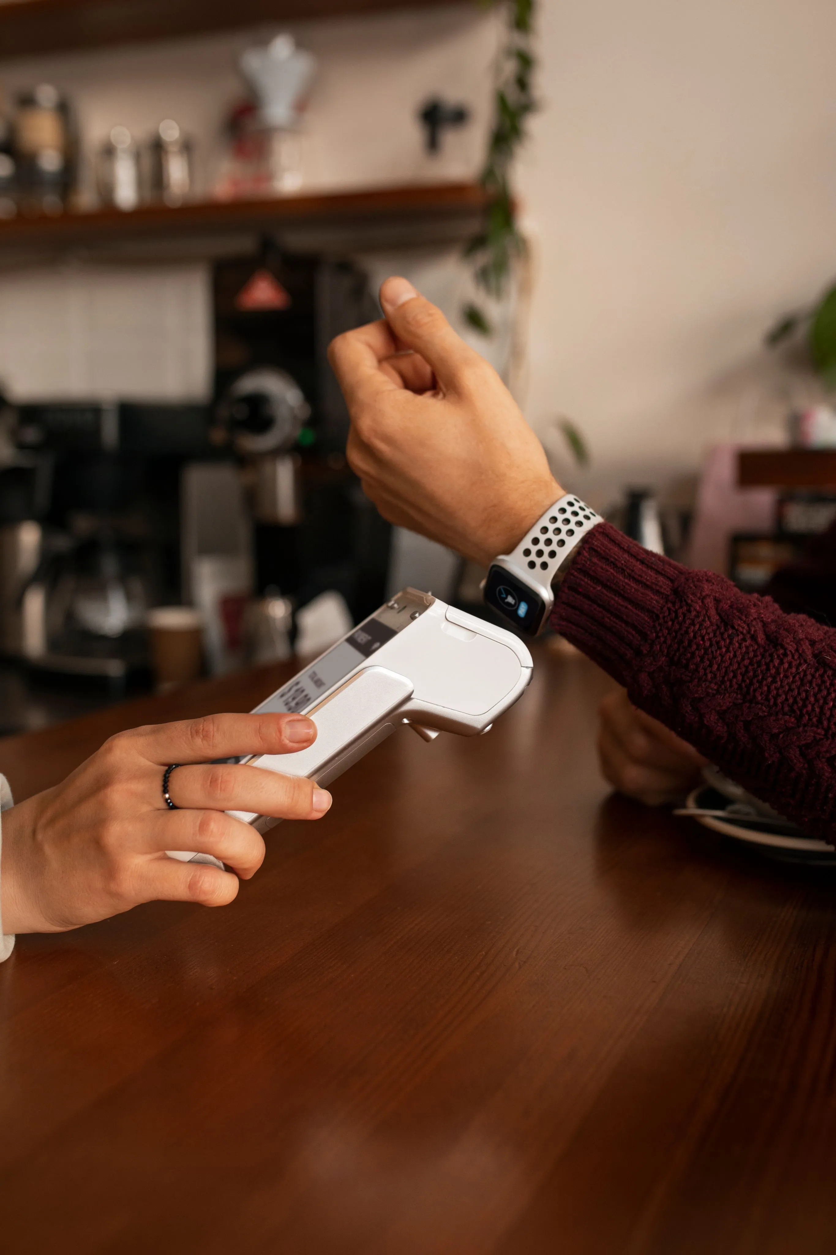 A customer tapping their card to pay at a cafe counter